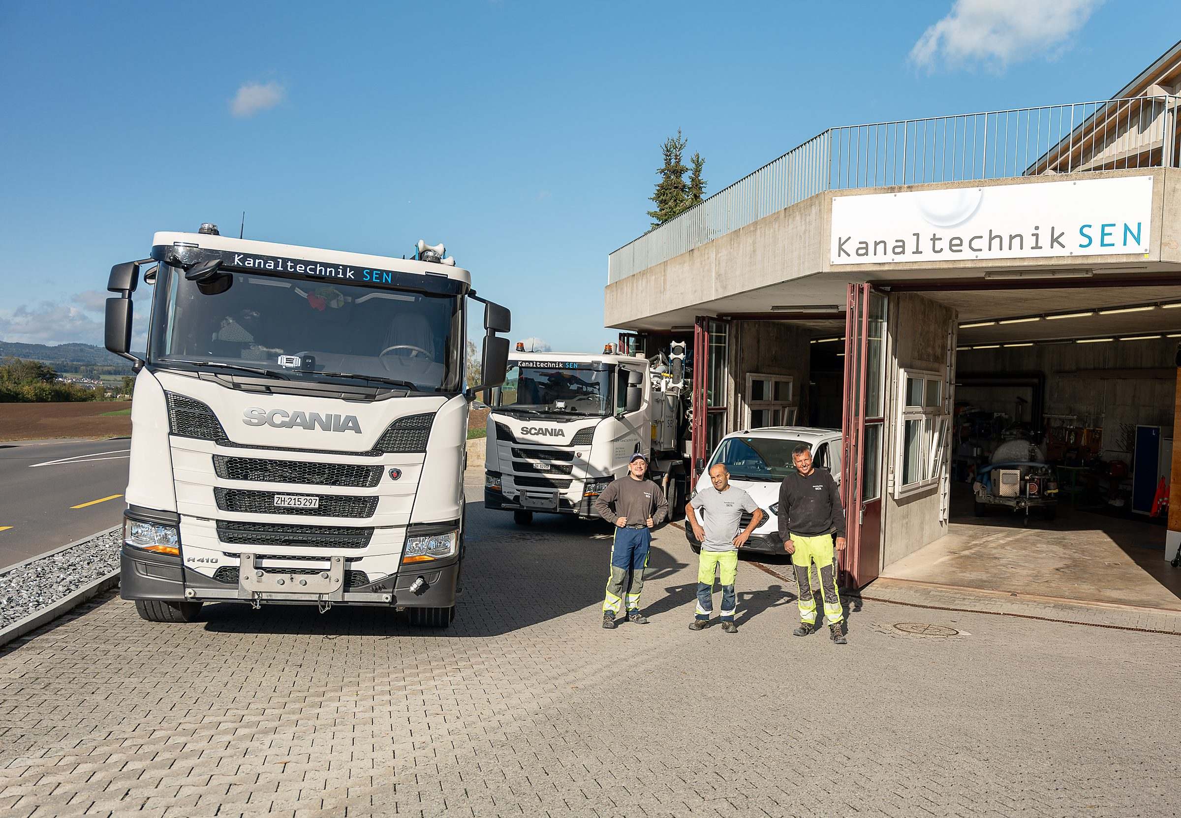 Firmengebäude der SEN Kanaltechnik in Obfelden mit den Saug- und Spülwagen und dem Team davor